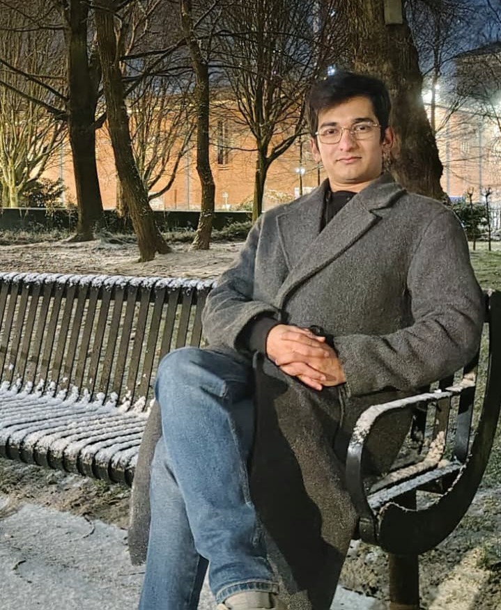 Piyush seated on a snow-dusted bench in Manchester at night